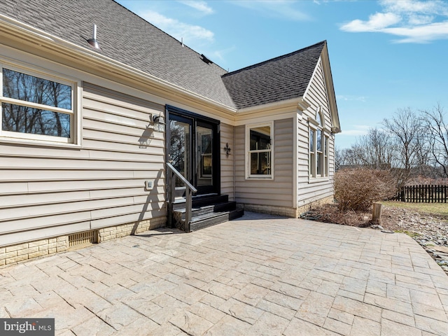 rear view of property featuring crawl space, a patio area, entry steps, and a shingled roof