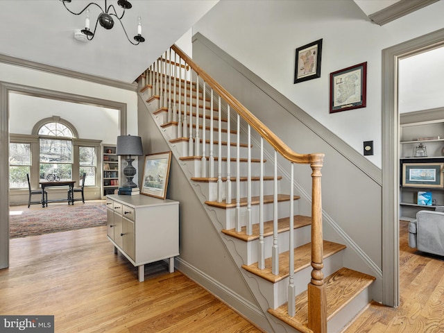 stairway featuring a notable chandelier, built in features, baseboards, and wood finished floors