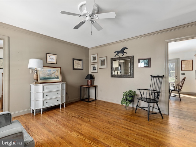 living area featuring wood finished floors, baseboards, and ornamental molding