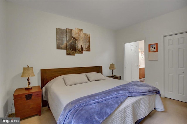 bedroom featuring ensuite bathroom, a closet, and light colored carpet