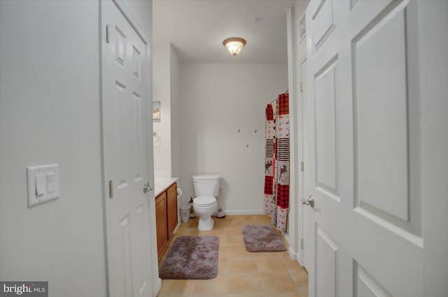 bathroom with curtained shower, toilet, vanity, baseboards, and tile patterned floors