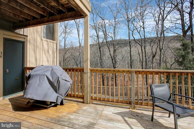 wooden terrace with a forest view and area for grilling