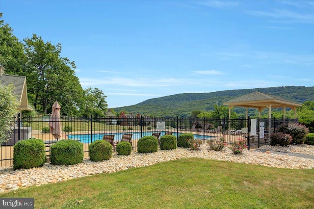 community pool featuring a gazebo, a lawn, fence, and a mountain view