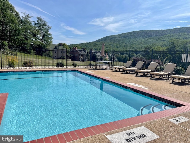 pool featuring fence, a patio, and a mountain view