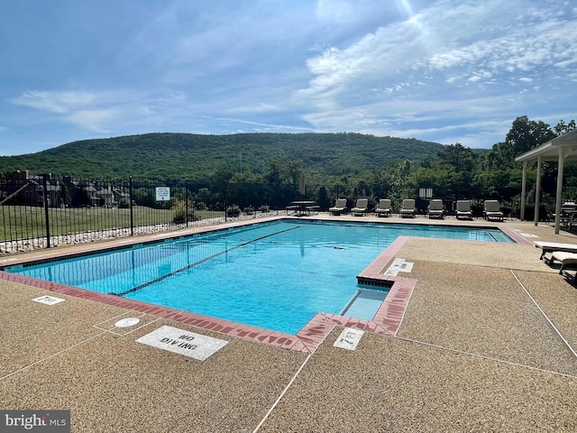 community pool featuring a patio, fence, and a mountain view