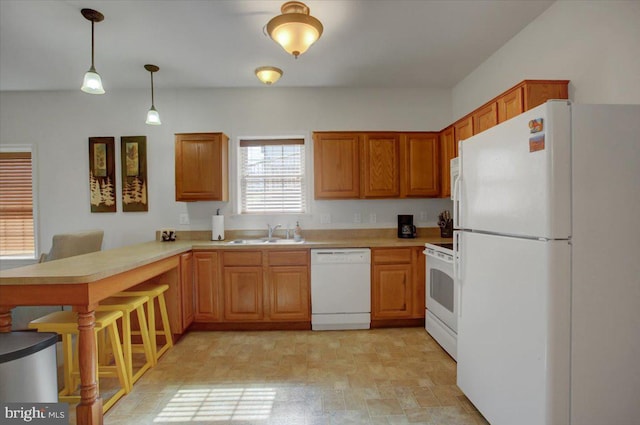 kitchen featuring a peninsula, white appliances, a sink, light countertops, and decorative light fixtures