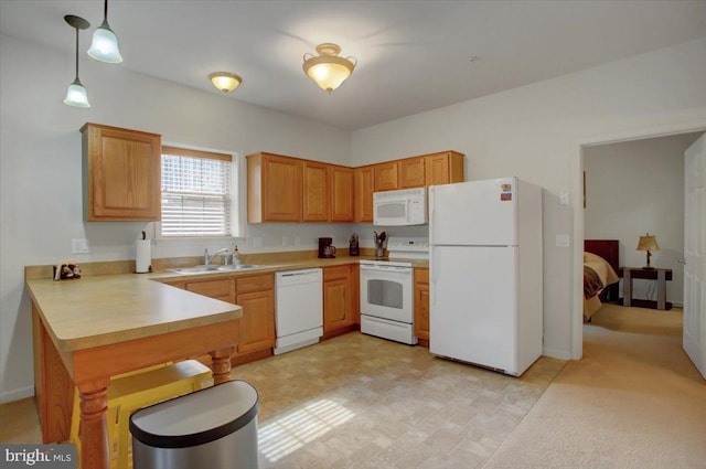 kitchen featuring a peninsula, white appliances, a sink, light countertops, and hanging light fixtures