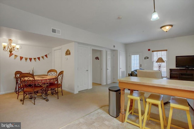 dining room featuring a chandelier, light colored carpet, visible vents, and baseboards