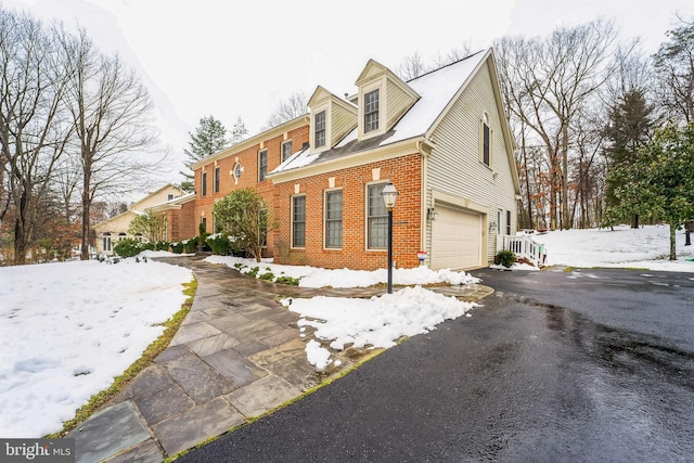 view of front facade featuring aphalt driveway, brick siding, and a garage