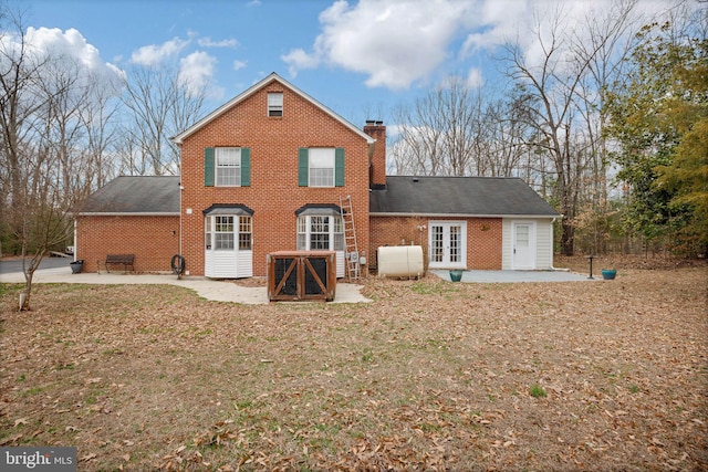 rear view of property featuring brick siding, a chimney, a patio, and french doors