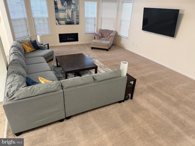 carpeted living area featuring a fireplace, baseboards, and a wealth of natural light