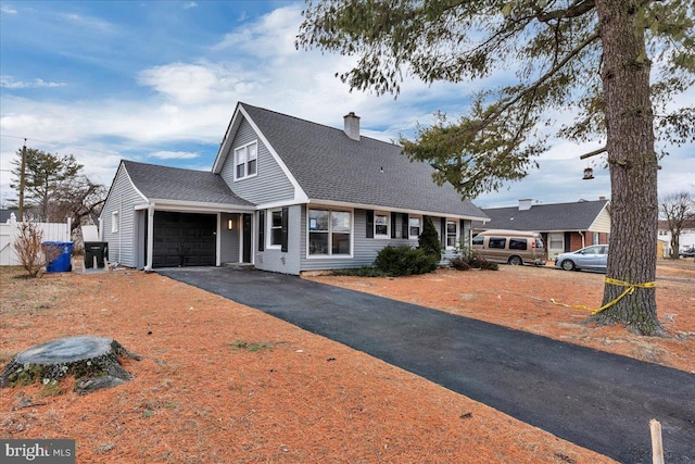 view of front of home featuring a chimney, aphalt driveway, roof with shingles, an attached garage, and fence