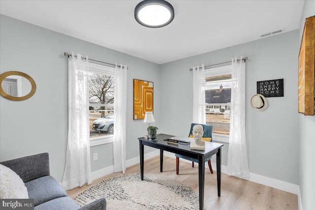 home office featuring light wood finished floors, visible vents, and baseboards