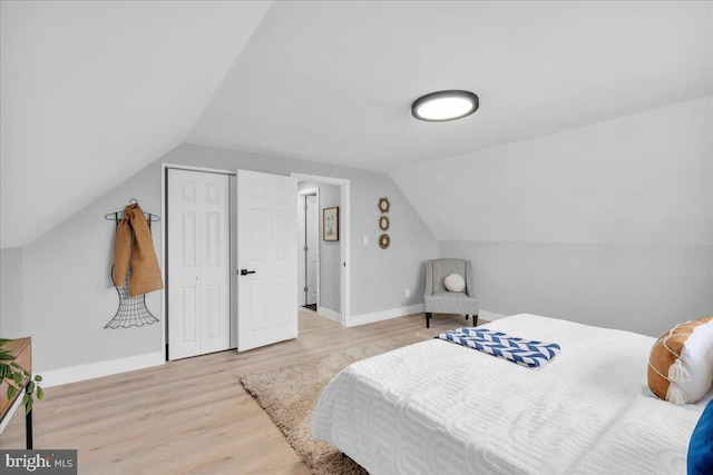 bedroom with vaulted ceiling, baseboards, and wood finished floors