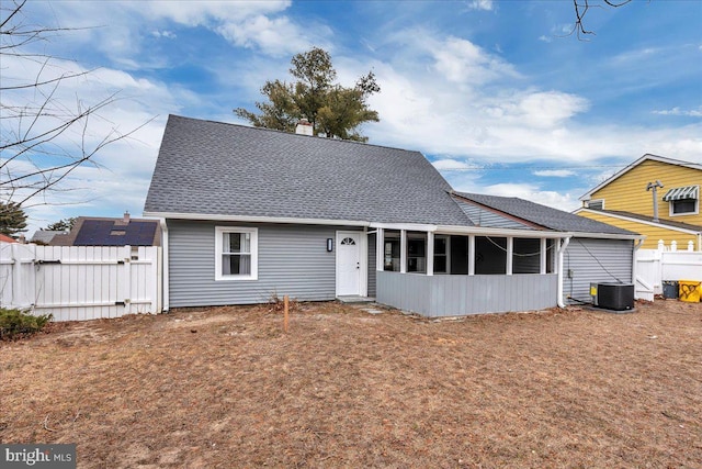 view of front facade featuring a shingled roof, a sunroom, fence, and a gate