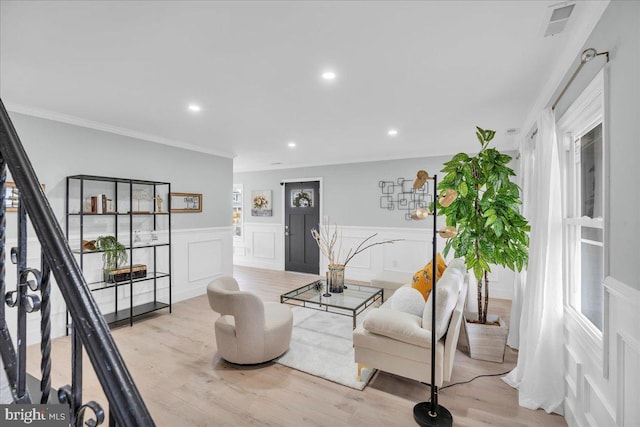 living room featuring ornamental molding, recessed lighting, wainscoting, and light wood-style flooring