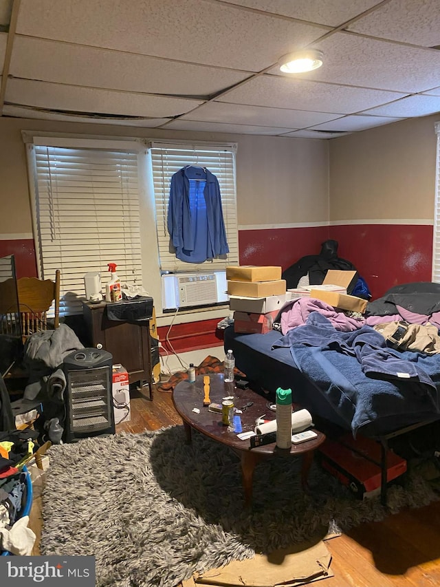 bedroom featuring cooling unit, a drop ceiling, and wood finished floors