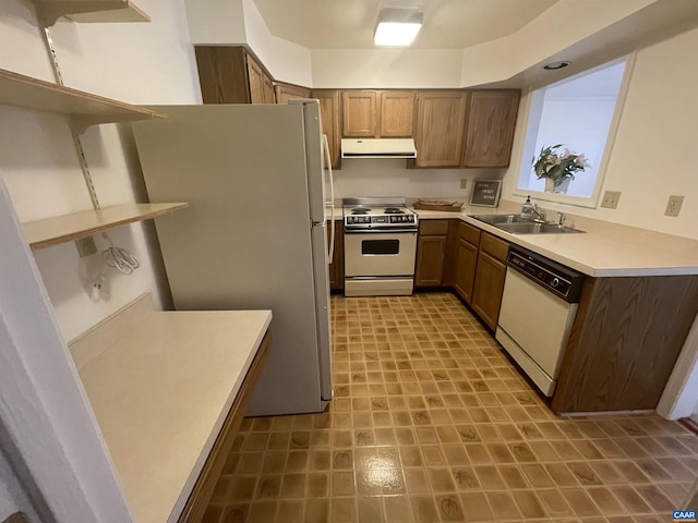 kitchen featuring light countertops, brown cabinetry, a sink, ventilation hood, and white appliances