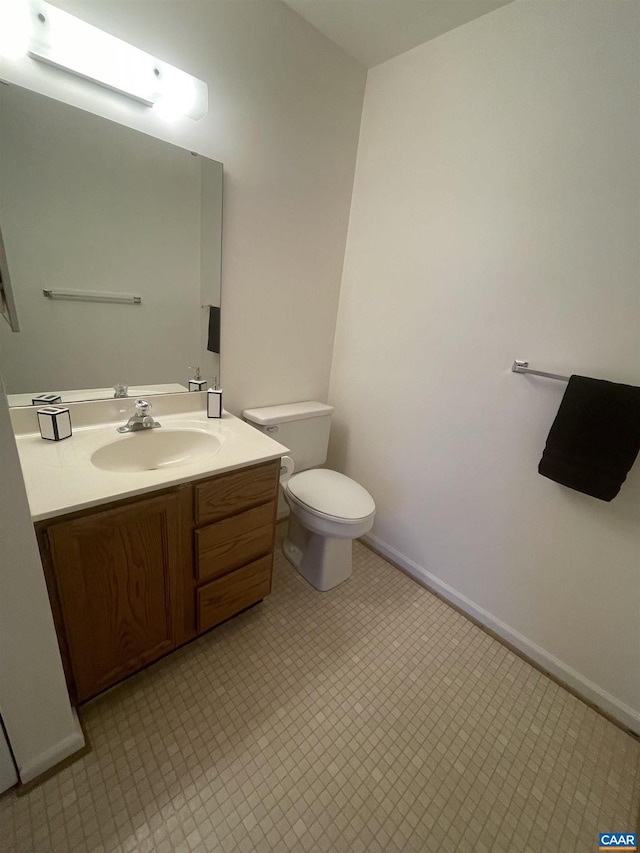 half bathroom with toilet, tile patterned floors, baseboards, and vanity