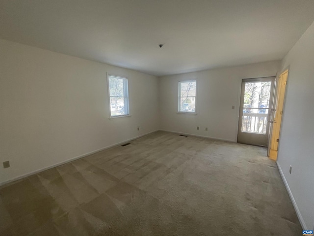 empty room featuring visible vents, baseboards, and light colored carpet