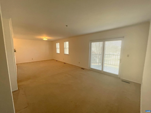 empty room with baseboards, visible vents, and light colored carpet