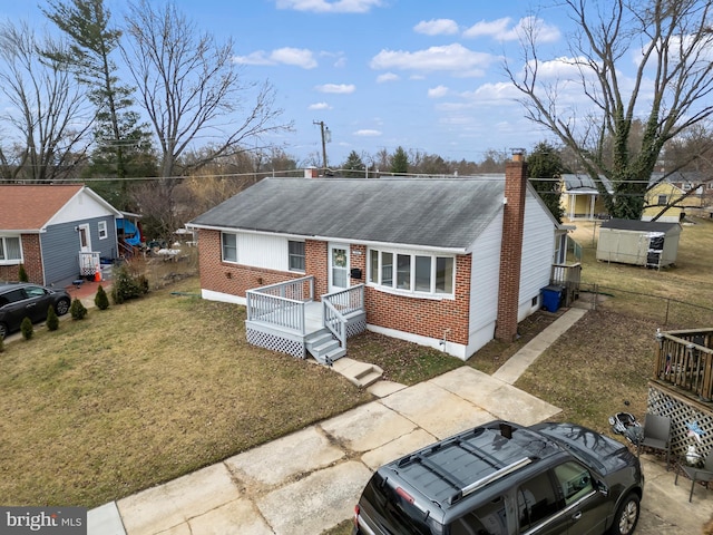 ranch-style house with a shingled roof, brick siding, a chimney, and a front lawn