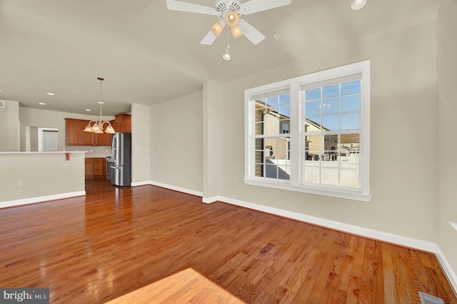 unfurnished living room with baseboards, dark wood finished floors, and ceiling fan with notable chandelier