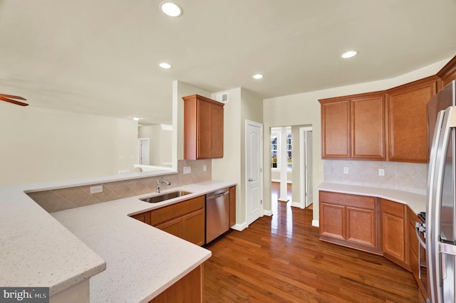 kitchen featuring appliances with stainless steel finishes, dark wood finished floors, a sink, and tasteful backsplash