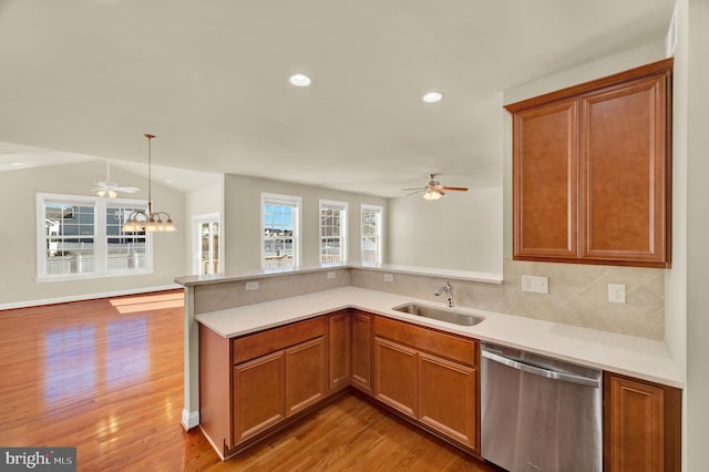 kitchen with tasteful backsplash, dishwasher, a peninsula, light countertops, and a sink