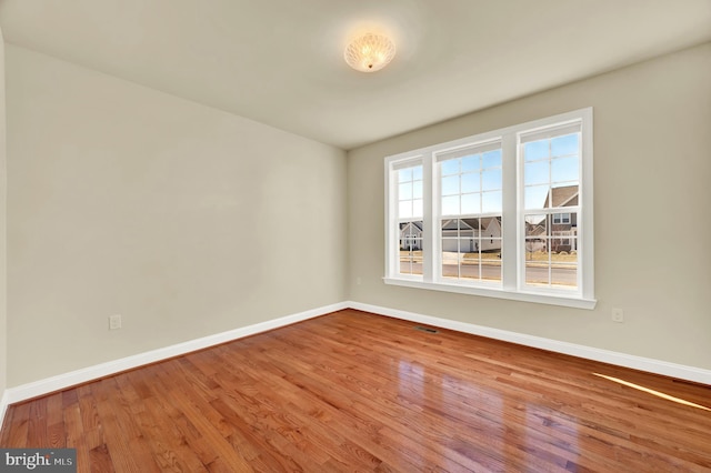 spare room with visible vents, baseboards, and wood finished floors