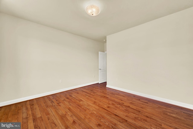 spare room featuring baseboards and wood finished floors