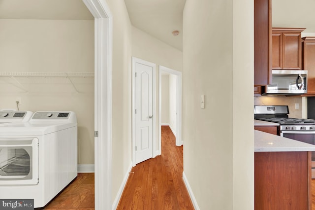 laundry room with light wood-type flooring, laundry area, baseboards, and separate washer and dryer