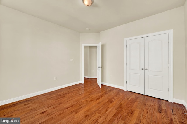 unfurnished bedroom with a closet, light wood-type flooring, and baseboards