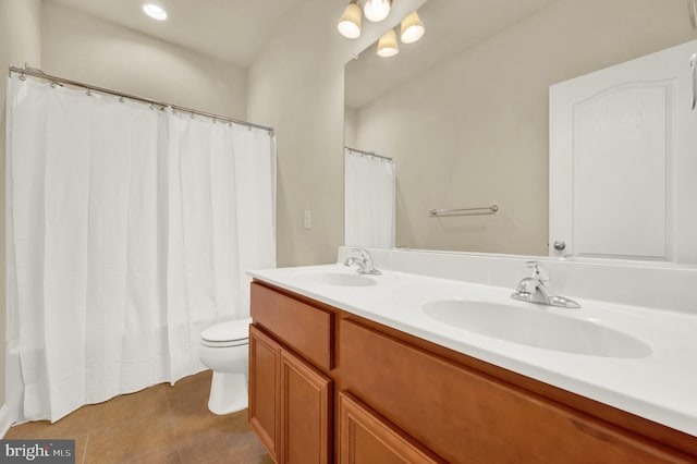 full bathroom featuring toilet, double vanity, a sink, and tile patterned floors