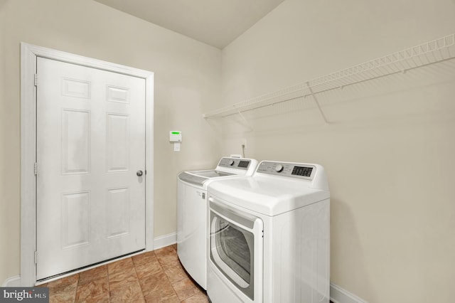 clothes washing area with laundry area, washing machine and dryer, and baseboards