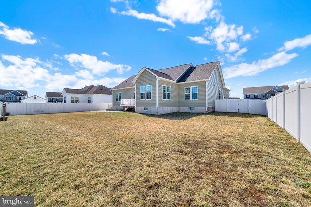 back of house with a fenced backyard and a lawn