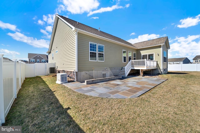 rear view of house featuring a lawn, a patio, a fenced backyard, a wooden deck, and central AC