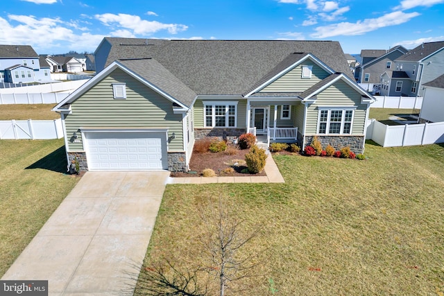 view of front of home with driveway, stone siding, fence, a front lawn, and a porch