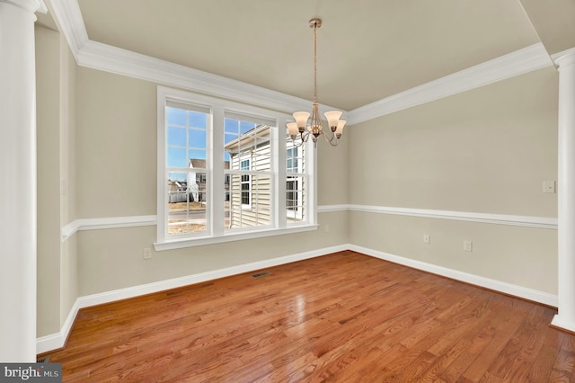 unfurnished dining area featuring ornate columns, baseboards, wood finished floors, and crown molding