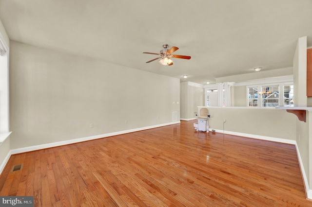 unfurnished living room with a ceiling fan, baseboards, visible vents, and wood finished floors