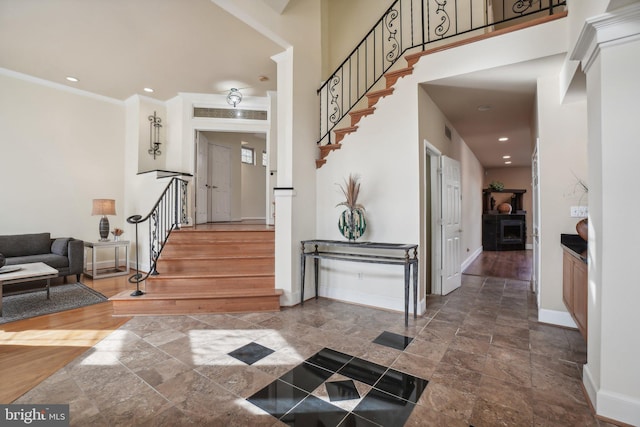 entryway featuring recessed lighting, stairs, baseboards, and a towering ceiling