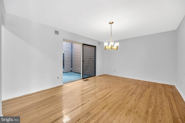 spare room with light wood-style floors, visible vents, baseboards, and an inviting chandelier