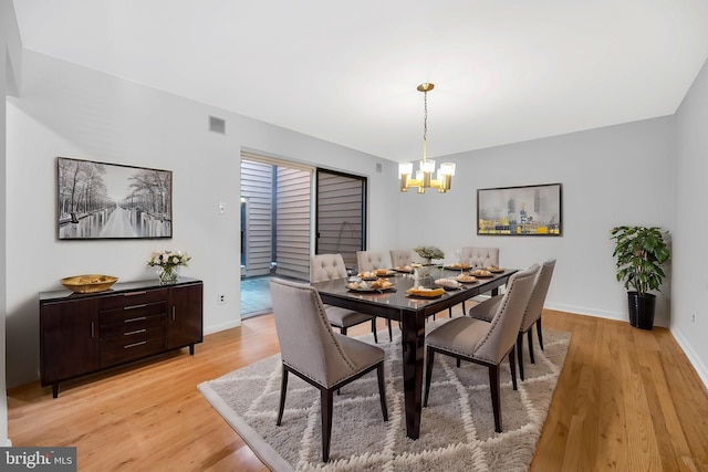 dining area featuring light wood-style floors, baseboards, and a chandelier