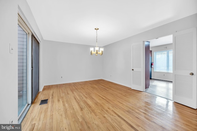 interior space featuring baseboards, light wood-type flooring, visible vents, and an inviting chandelier