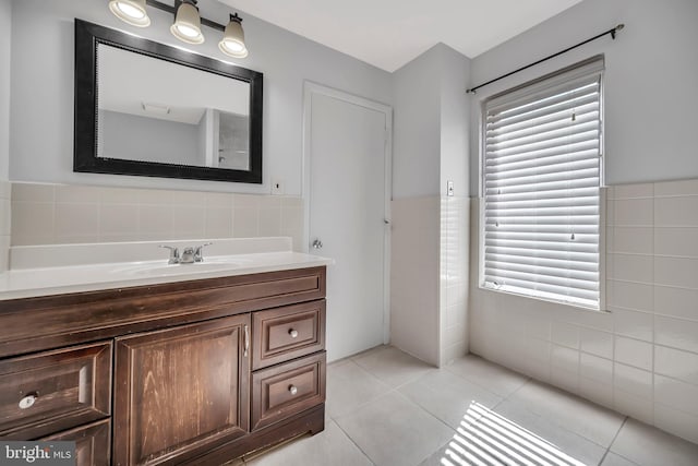 bathroom with a wainscoted wall, tile walls, vanity, and tile patterned floors