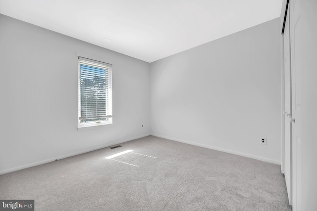 spare room with carpet, visible vents, and baseboards