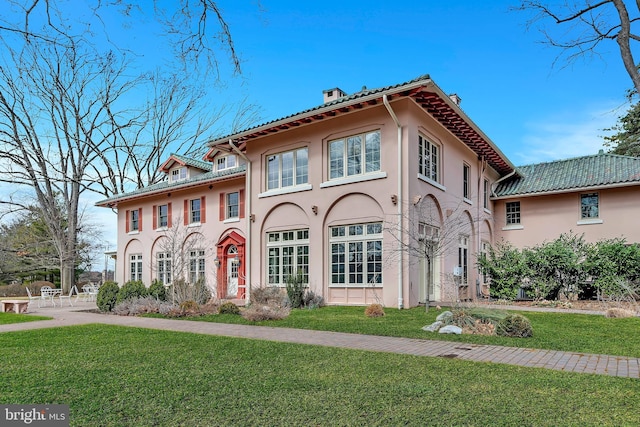 view of front of house featuring a chimney, a front lawn, and stucco siding