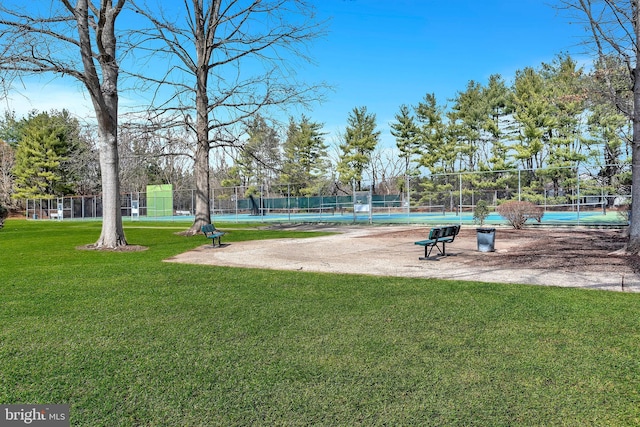 surrounding community featuring a tennis court, fence, and a lawn