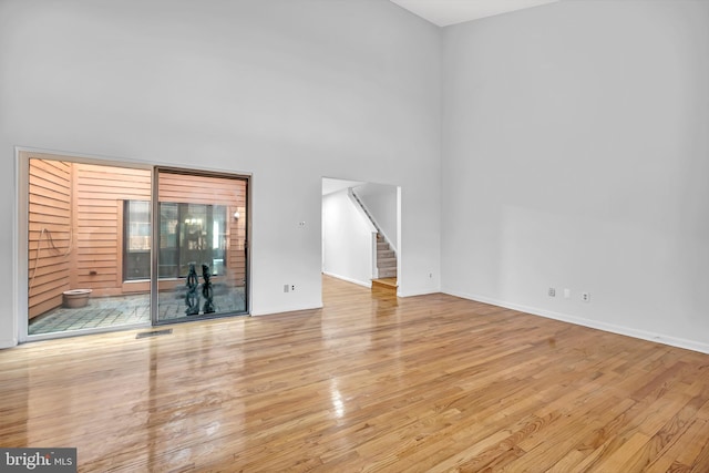 unfurnished living room featuring baseboards, stairs, visible vents, and wood finished floors