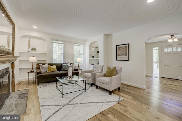 living area with arched walkways, built in features, recessed lighting, baseboards, and hardwood / wood-style flooring